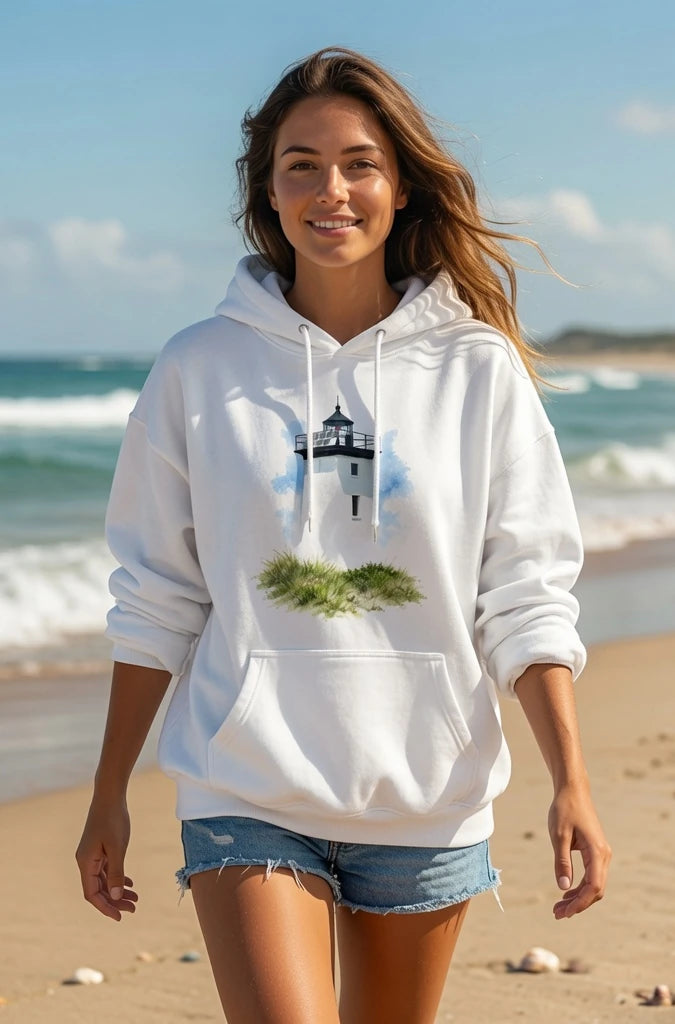 Woman wearing a white hoodie with a lighthouse design on a beach